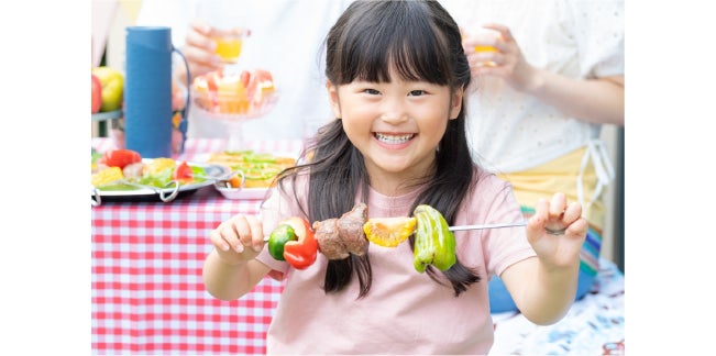 バーベキューのお肉を持って嬉しそうな女の子